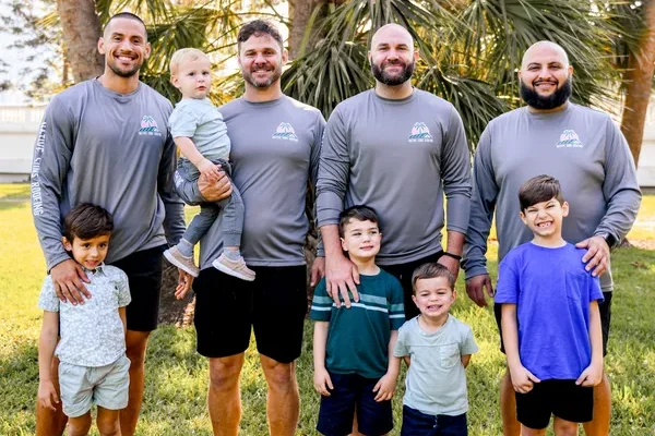 The Native Sons Roofing team standing together with their sons, smiling for a group photo.